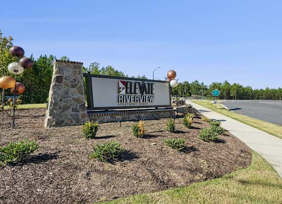 A sign for Heviq Riverview in front of a road.