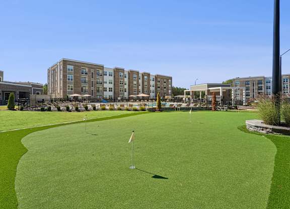 A golf course with a green lawn and a flag on the green.