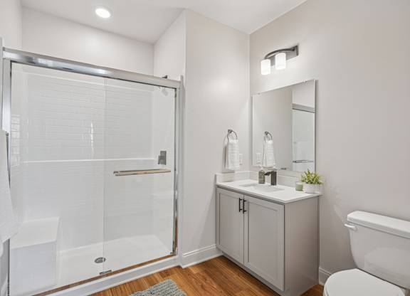 A white bathroom with a walk-in shower, toilet, and sink.