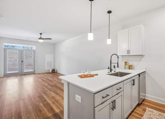 A kitchen with a white countertop and wooden floors.