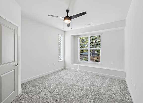 A room with a ceiling fan and a window with blinds.