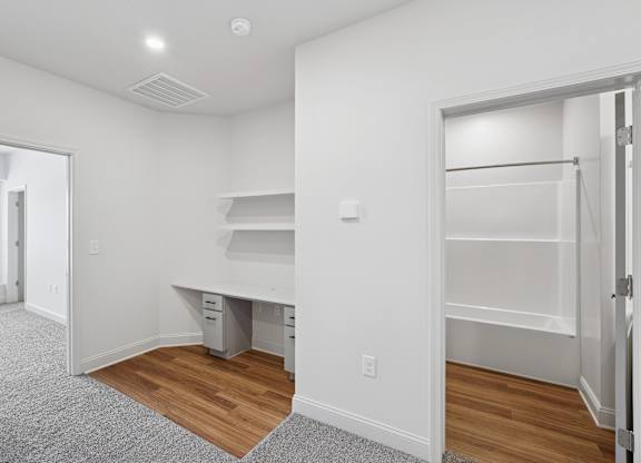 A white room with a desk and drawers.