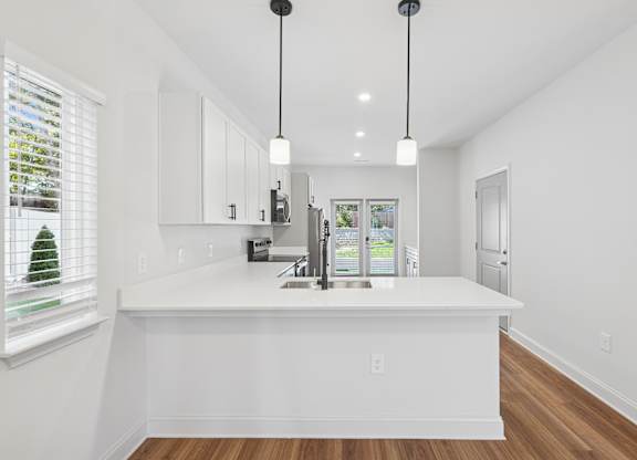 A kitchen with white cabinets and a white island.