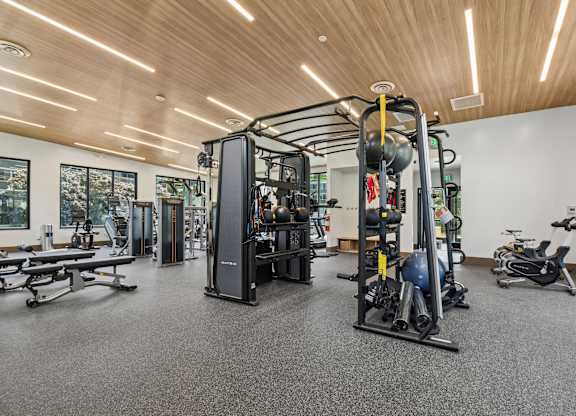 A gym with a variety of equipment including a weight machine, a bench press, and a rowing machine.