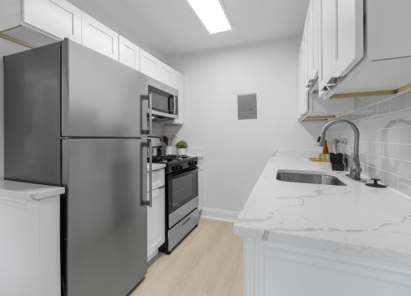a kitchen with white countertops and stainless steel appliances