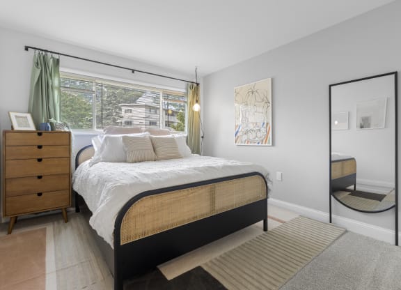 a bedroom with a large window and a large bed with a white comforter