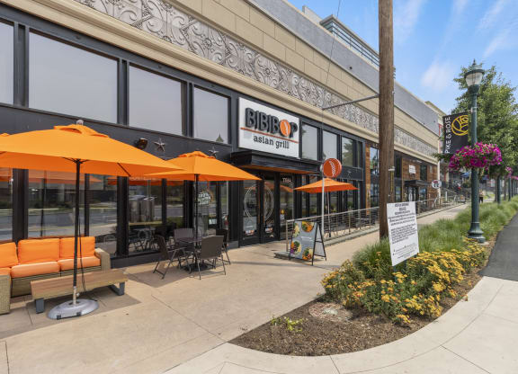 a sidewalk outside of a building with orange umbrellas