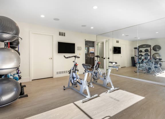 a workout room with bikes and mirrors in a home gym