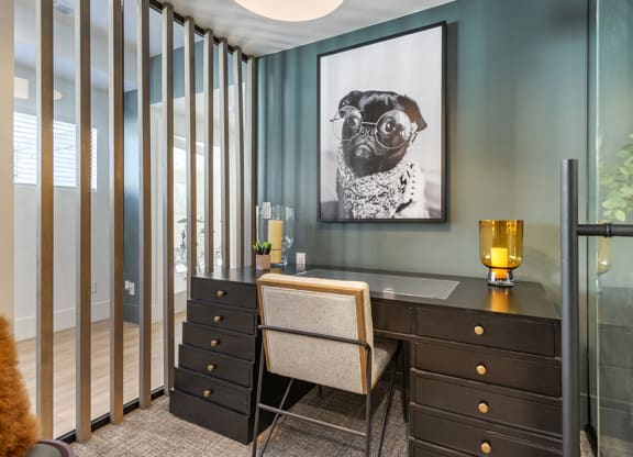 A room with a desk and a chair with a picture of a dog on the wall.