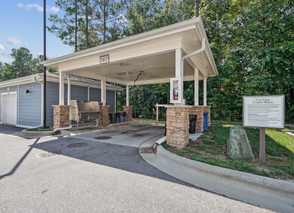 a covered pavilion with a picnic table in front of a parking lot