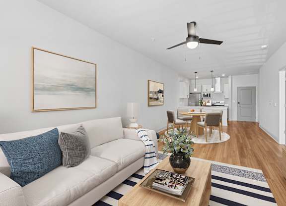 A living room with a white couch and a painting on the wall.