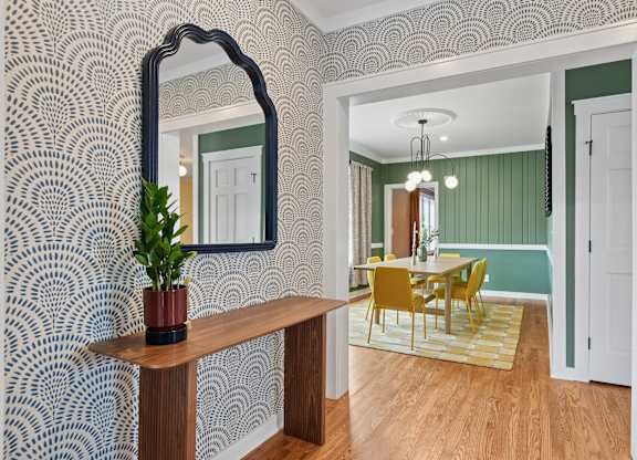 A room with a mirror, a table, and chairs.