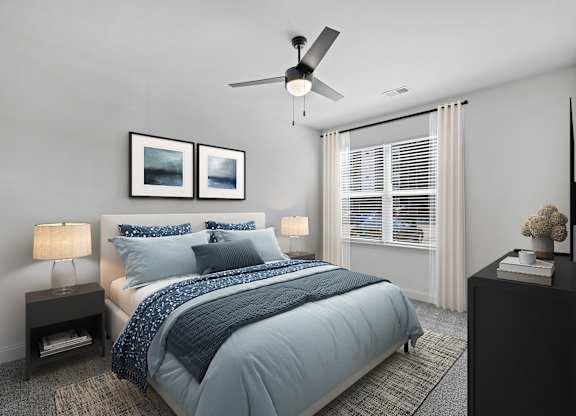 A bedroom with a bed, two lamps, a ceiling fan, and two pictures on the wall.