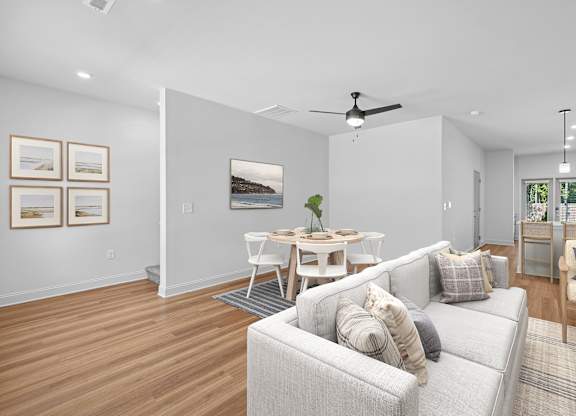 A living room with a grey couch and a dining table.