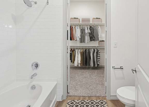 A white bathroom with a walk in closet.