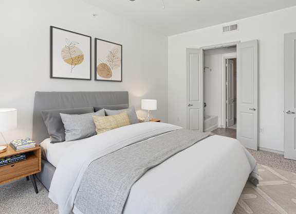 A bedroom with a large bed and two framed pictures on the wall.