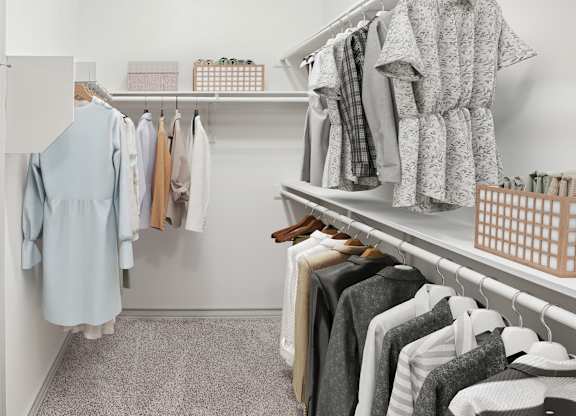 A white closet with clothes hanging and shelves with boxes.