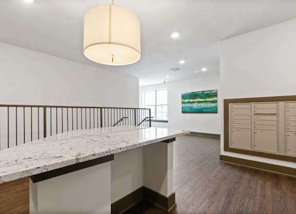 a white kitchen with a marble counter top and a staircase