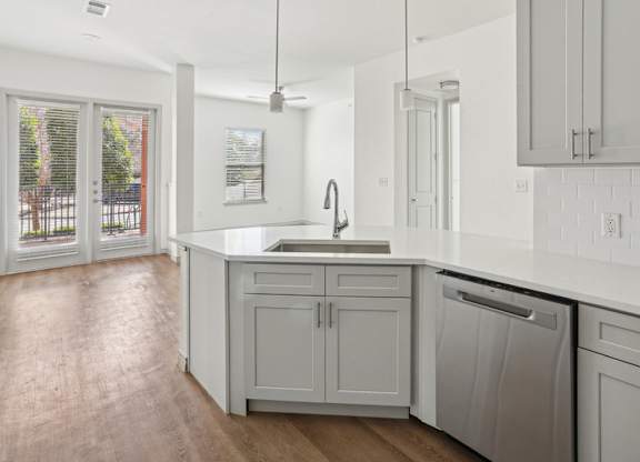 A kitchen with white cabinets and a wooden floor.