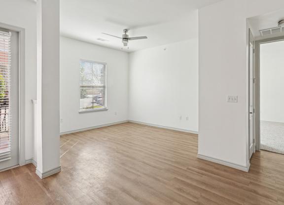 A room with a ceiling fan and a window with blinds.