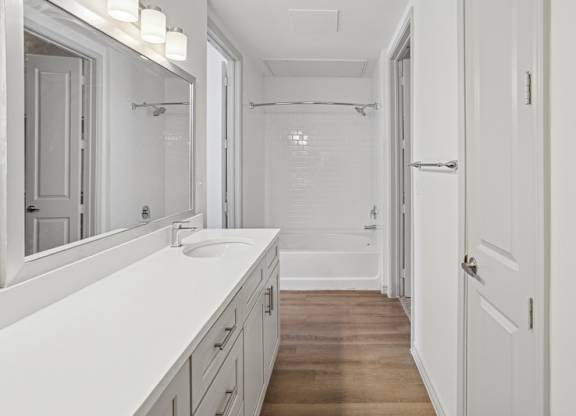 A white bathroom with a sink and mirror.