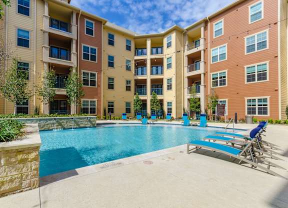 an apartment building with a swimming pool and lounge chairs