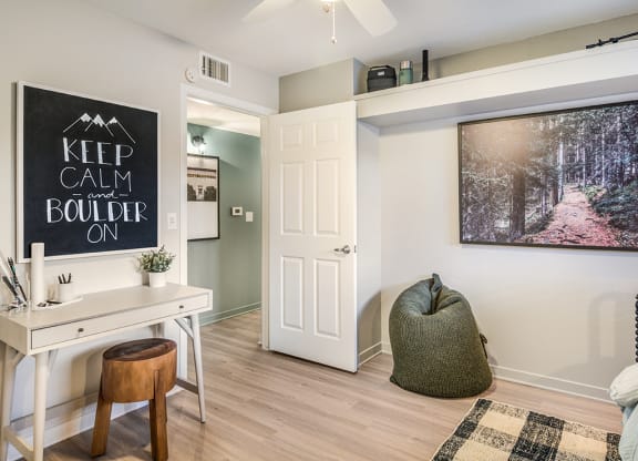 A room with a desk, chair, and a large poster on the wall.