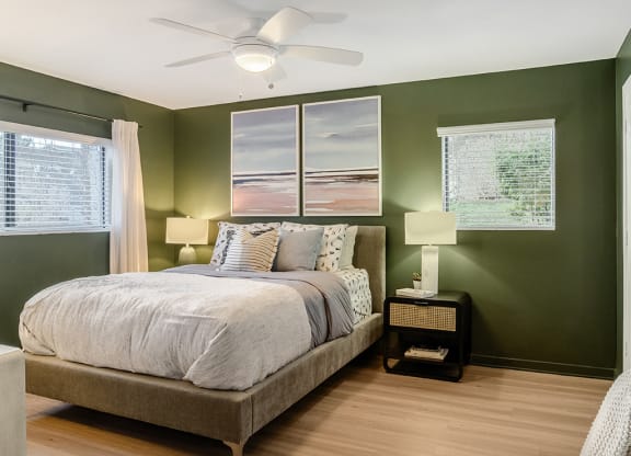 a bedroom with green walls and a ceiling fan