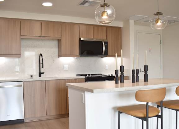 Modern kitchen with white island and bar stools at Garden at 3Roots Apartments, California