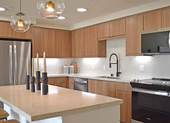 Modern kitchen with wood cabinetry and white countertops at Garden at 3Roots Apartments, San Diego, CA