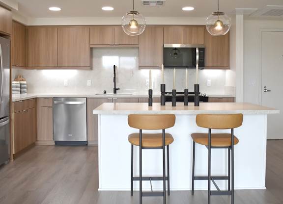 Contemporary kitchen with island seating and globe pendants at Garden at 3Roots Apartments, San Diego, 92126