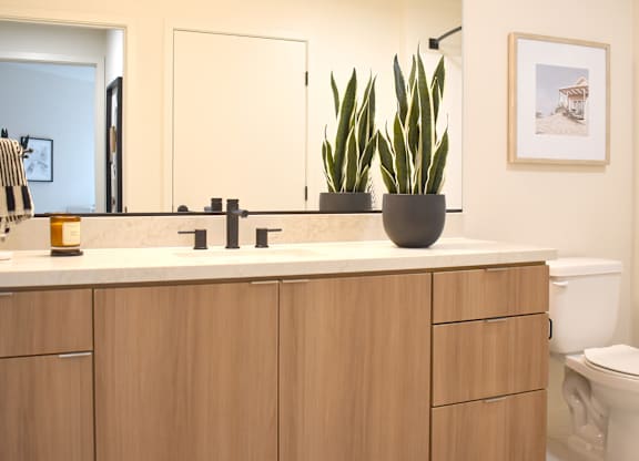 Bathroom with wood vanity and white quartz countertop at Garden at 3Roots Apartments, San Diego, CA 92126