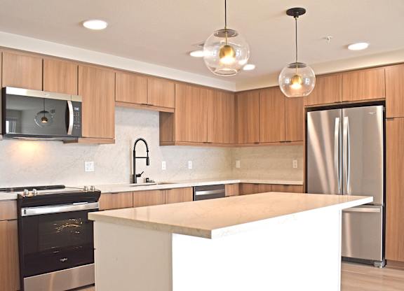 Kitchen with light wood cabinets and center island at Garden at 3Roots Apartments, San Diego, CA