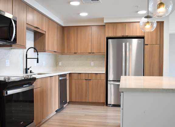 Kitchen with wood cabinetry and stainless appliances at Garden at 3Roots Apartments, San Diego, 92126