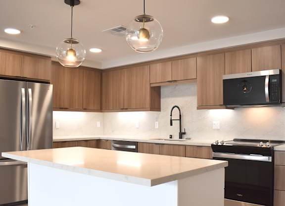 Modern kitchen with white island and pendant lights at Garden at 3Roots Apartments, San Diego, California