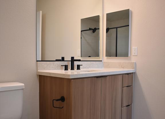 Bathroom with wood vanity and black fixtures at Garden at 3Roots Apartments, San Diego