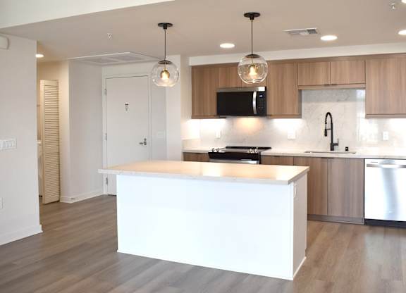 Open kitchen with island and wood cabinetry at Garden at 3Roots Apartments, California