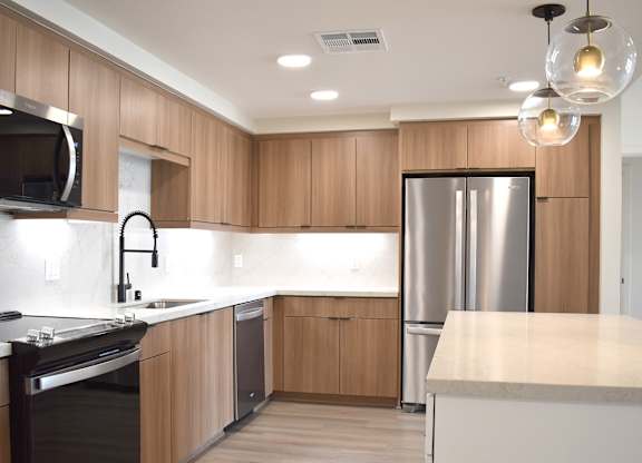 Contemporary kitchen with wood cabinets and island at Garden at 3Roots Apartments, California, 92126
