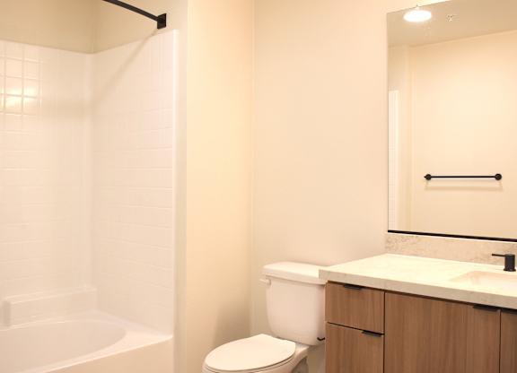 Bathroom with white tiled tub and shower at Garden at 3Roots Apartments, San Diego, CA