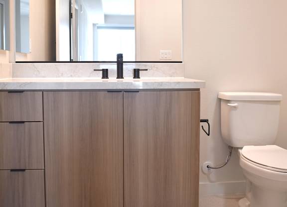 Modern bathroom with wood vanity and wall mirror at Garden at 3Roots Apartments, San Diego, 92126