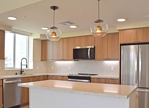 Kitchen with globe pendant lights and marble countertop at Garden at 3Roots Apartments, San Diego, California