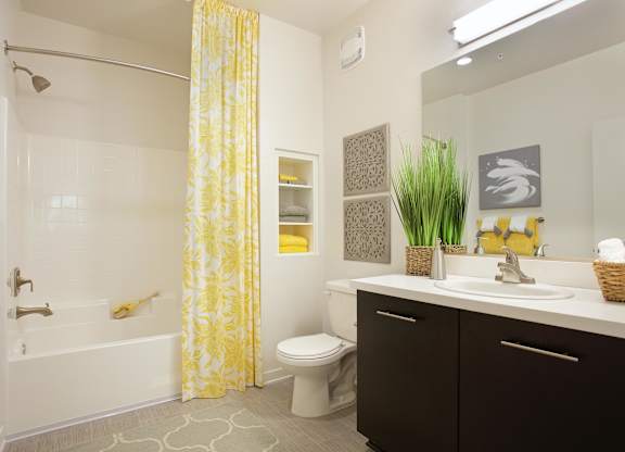 Bathroom with yellow patterned shower curtain and dark vanity at Casa Mira View Apartments, San Diego, CA 92126