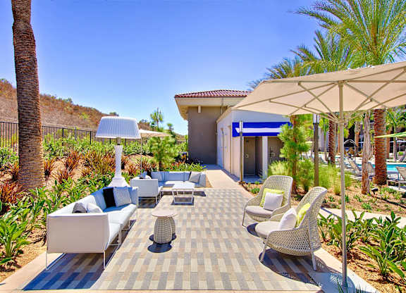 Outdoor patio lounge with wicker seating and umbrellas at Casa Mira View Apartments, California, 92126