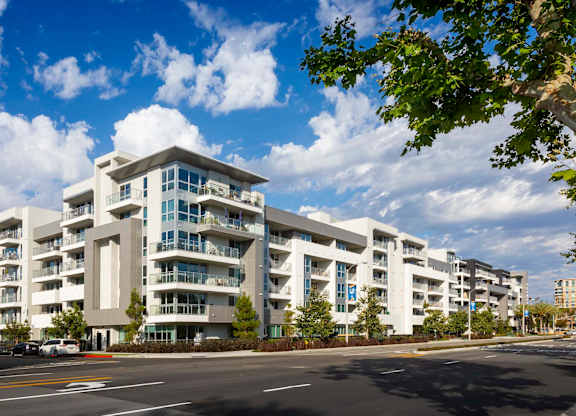 Modern white apartment building with balconies and street view at Elements Apartments, Irvine, 92612