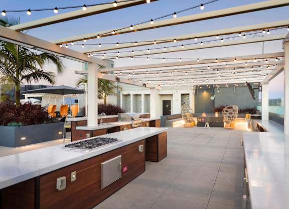 Outdoor rooftop kitchen with cooking stations and string lights at Elements Apartments, Irvine, 92612