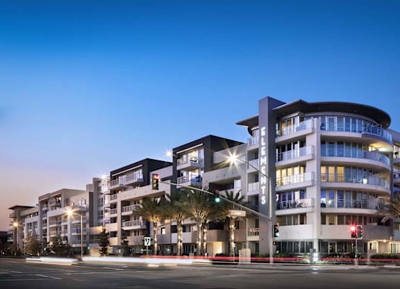 Modern apartment building exterior at twilight with curved balconies at Elements Apartments, Irvine
