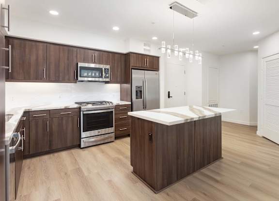 Kitchen with island stainless appliances and modern chandelier at Elements Apartments, Irvine, California
