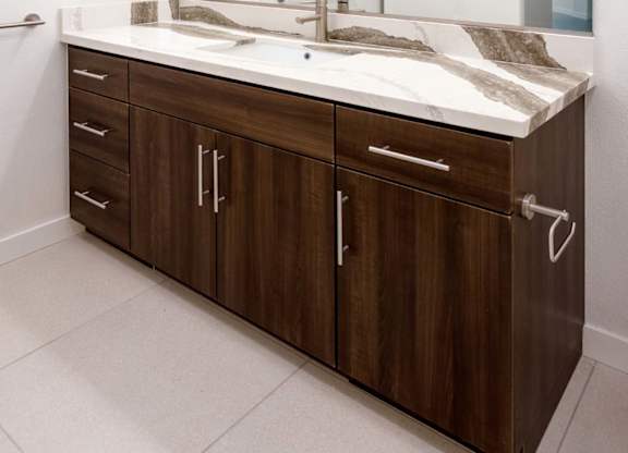 Double vanity bathroom with marble countertop and wood cabinetry at Elements Apartments, Irvine, 92612