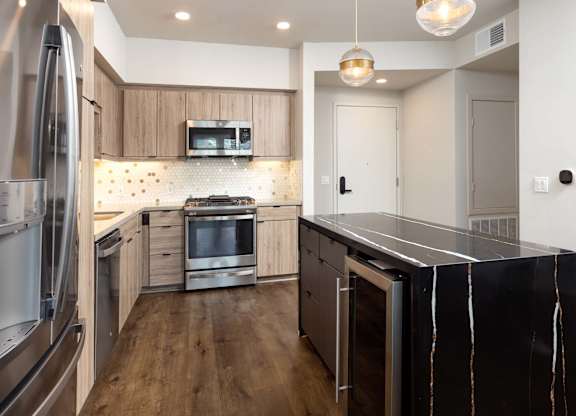 Modern kitchen with dark waterfall island and wood cabinets at Elements Apartments, Irvine, CA