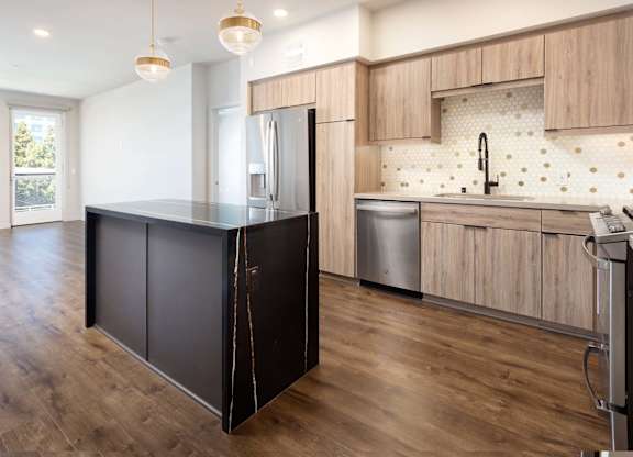 Kitchen with dark island and light wood cabinetry at Elements Apartments, Irvine, 92612